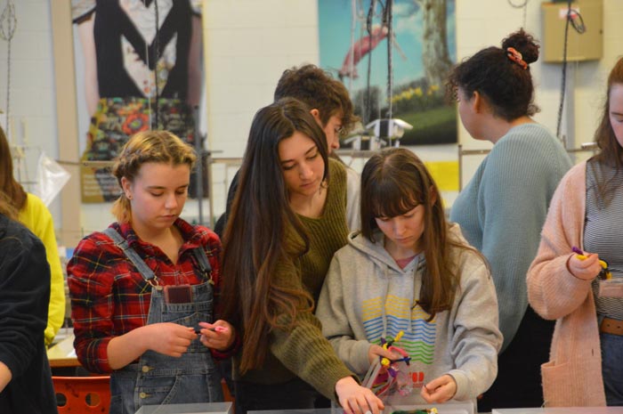 Three students are looking at their work.